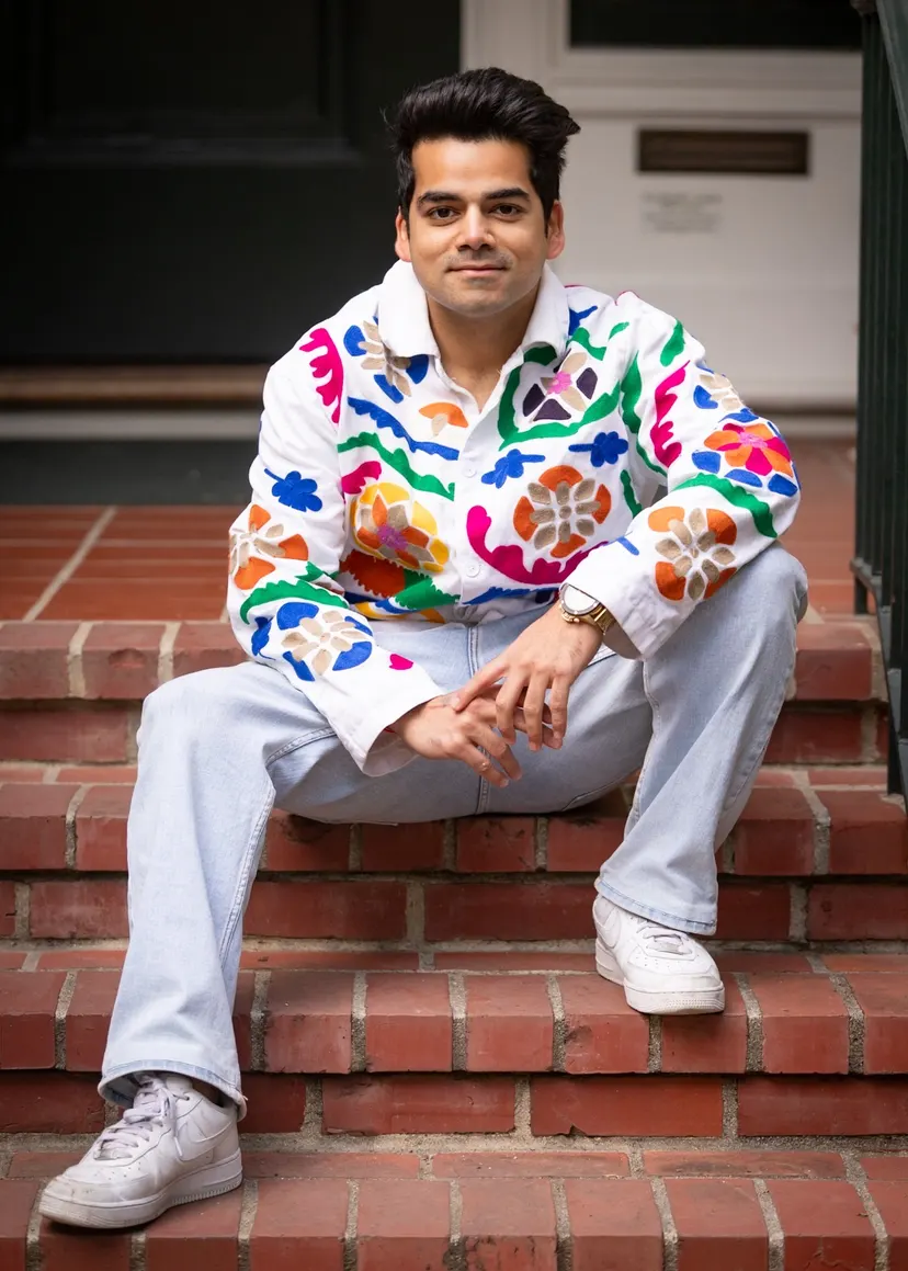 Kush in the embroidered jacket and white trousers, sitting on red brick steps